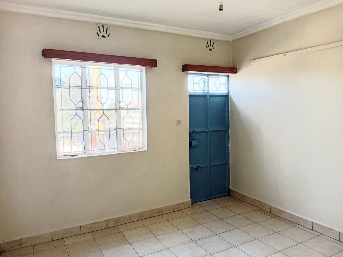 Unfurnished bedroom with patterned window and blue door
