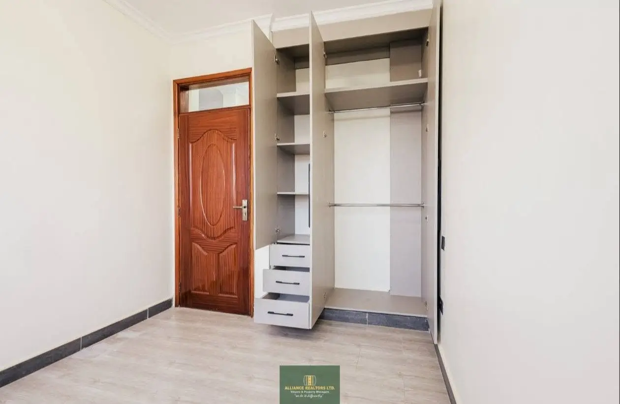 Empty bedroom with open built-in wardrobe and wooden door