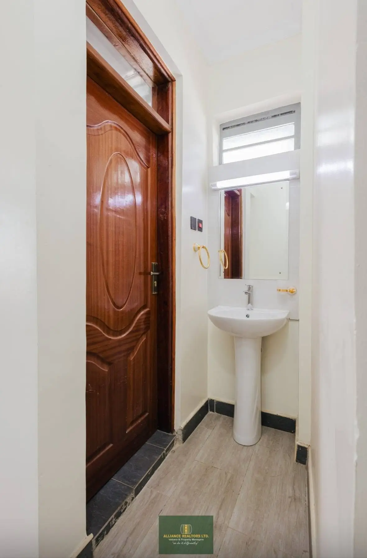 Small toilet room with pedestal sink and wooden door