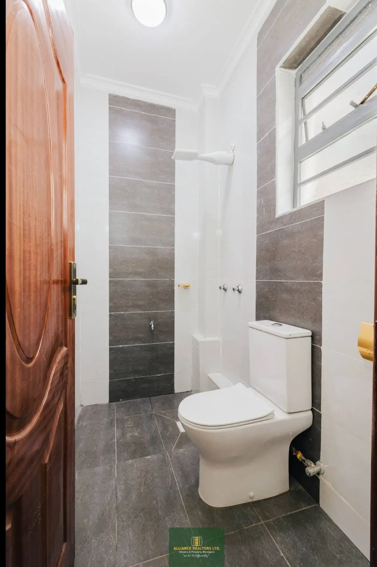 Compact bathroom with grey tiles, toilet and shower