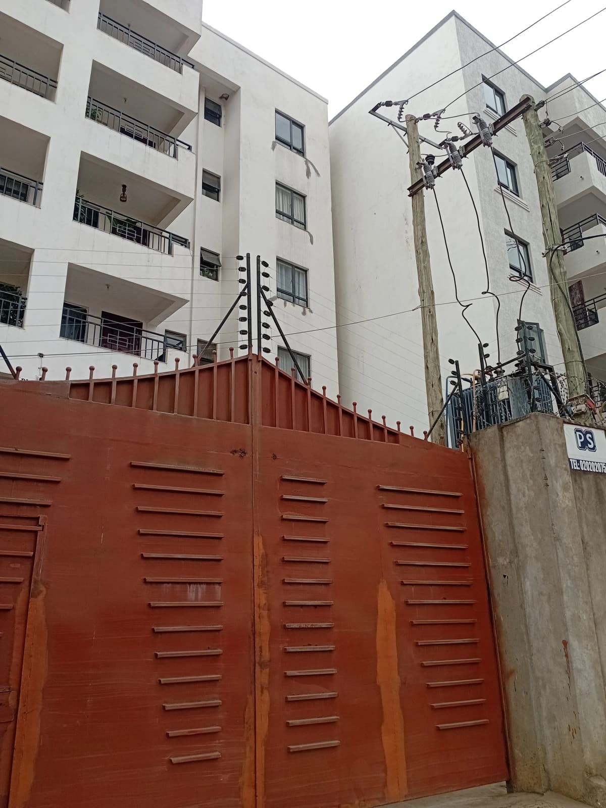 Multi-story residential building with red metal gate entrance