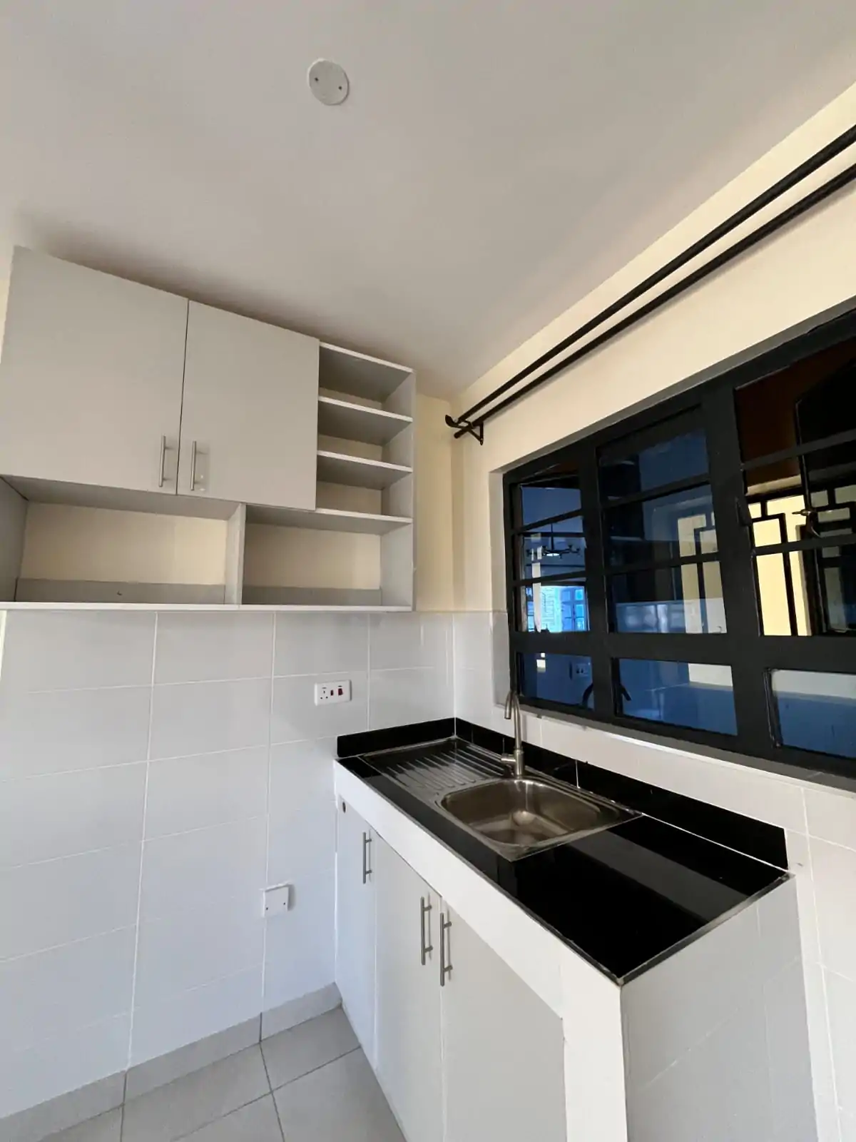 Modern kitchen with white cabinetry and black countertop sink