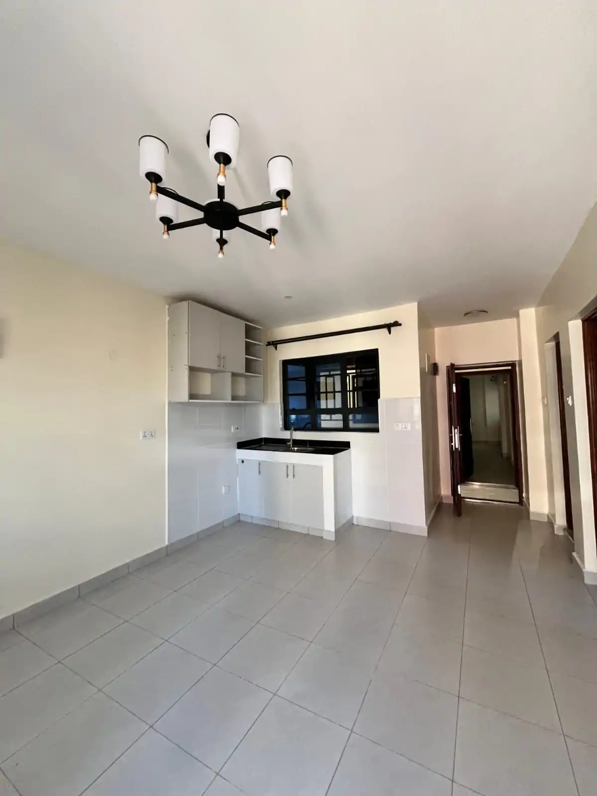 Open-plan living area with integrated kitchen counter and modern chandelier