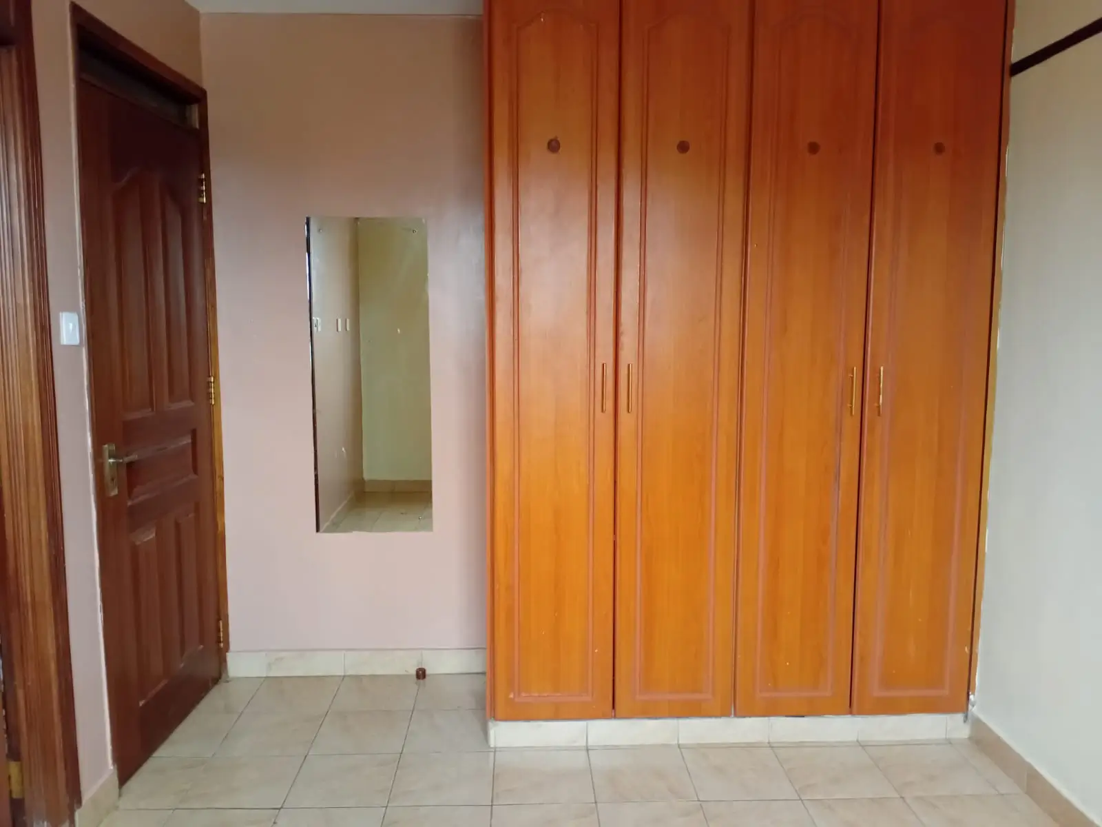 Bedroom with large wooden built-in wardrobe and tiled floor