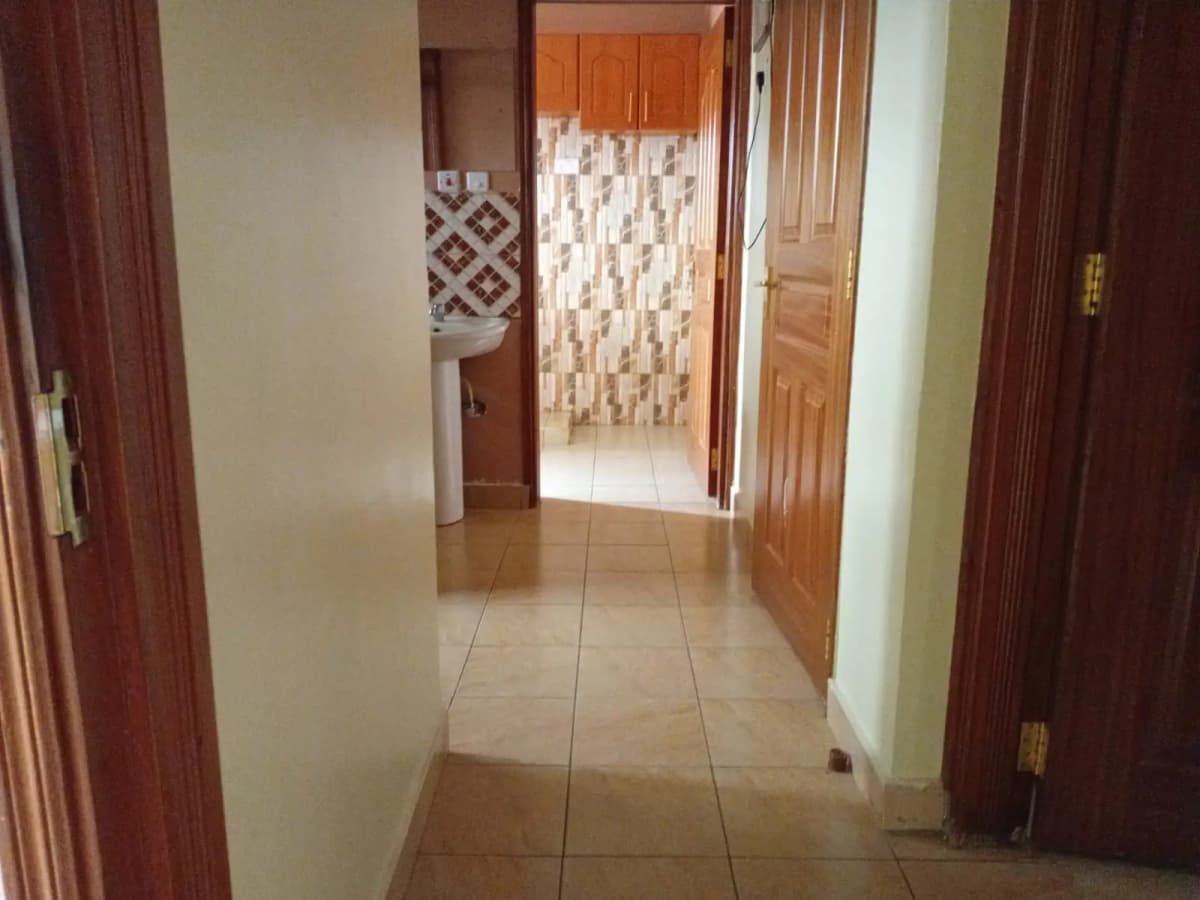 Tiled hallway with wooden doors and bathroom entrance visible