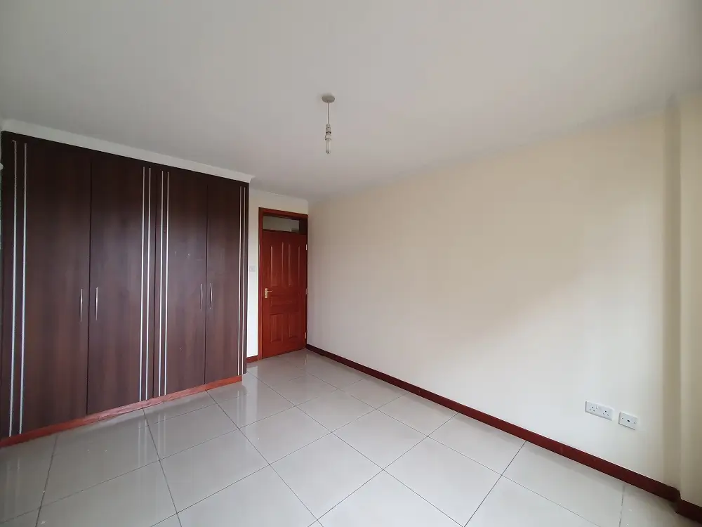 Spacious bedroom with dark wooden built-in wardrobes
