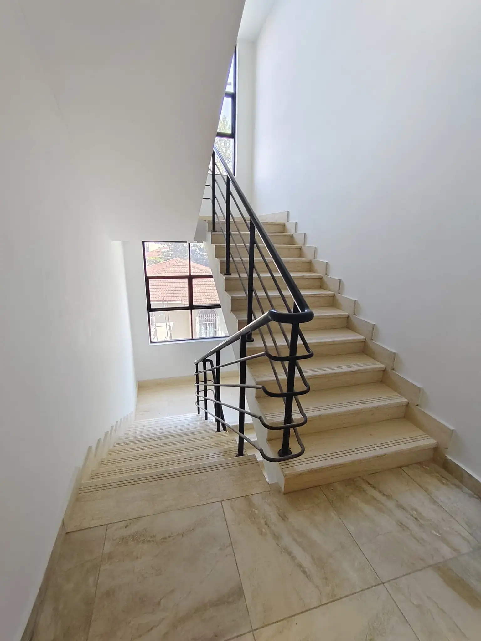 Modern stairwell with black metal railing and natural light