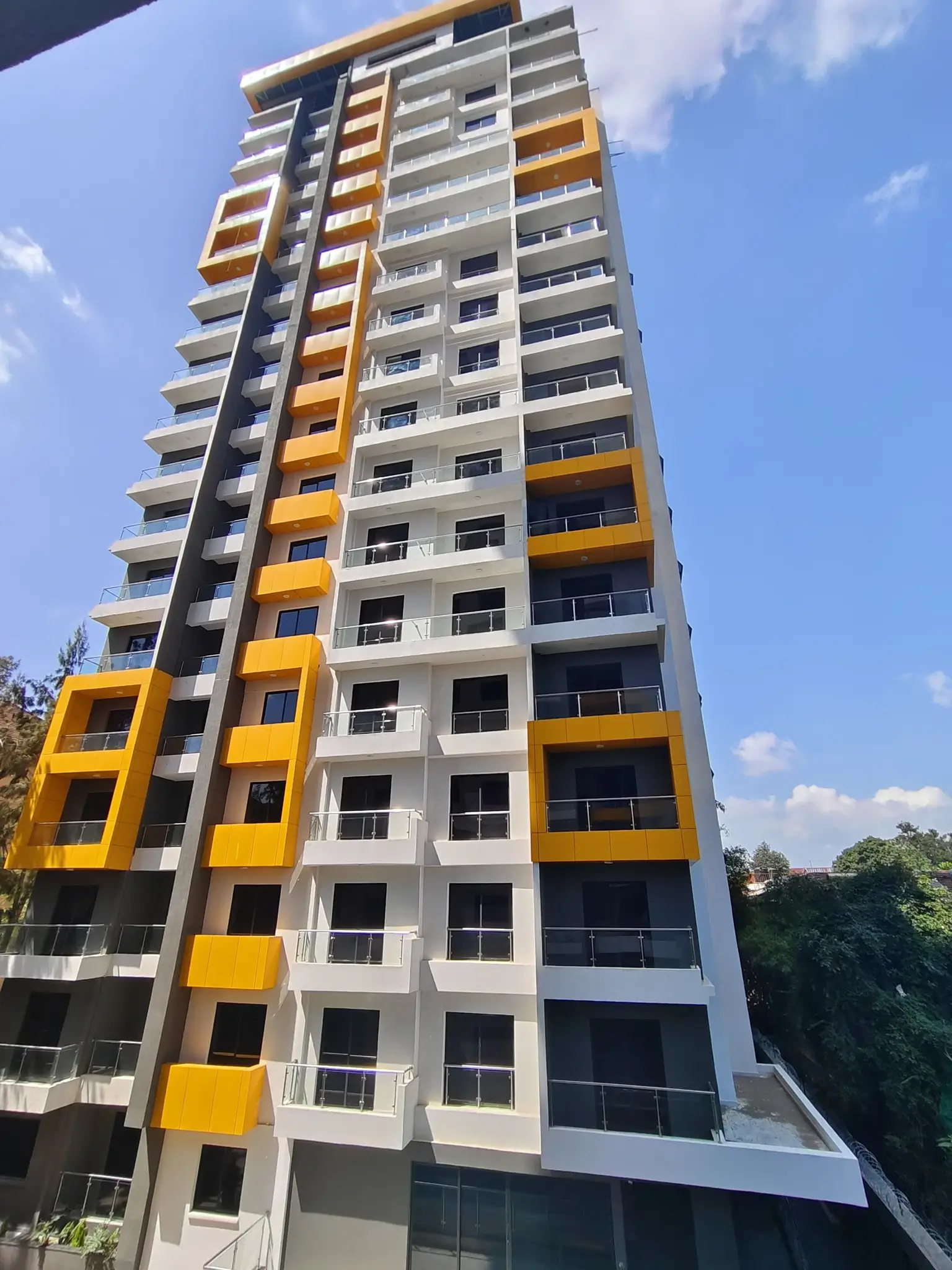 Modern multi-story residential building with yellow and white facade