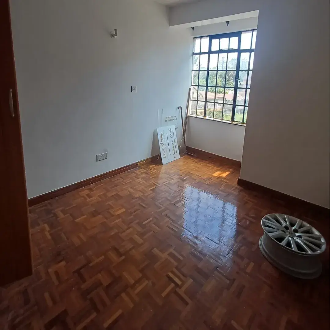 Spacious bedroom with herringbone wood flooring and large window