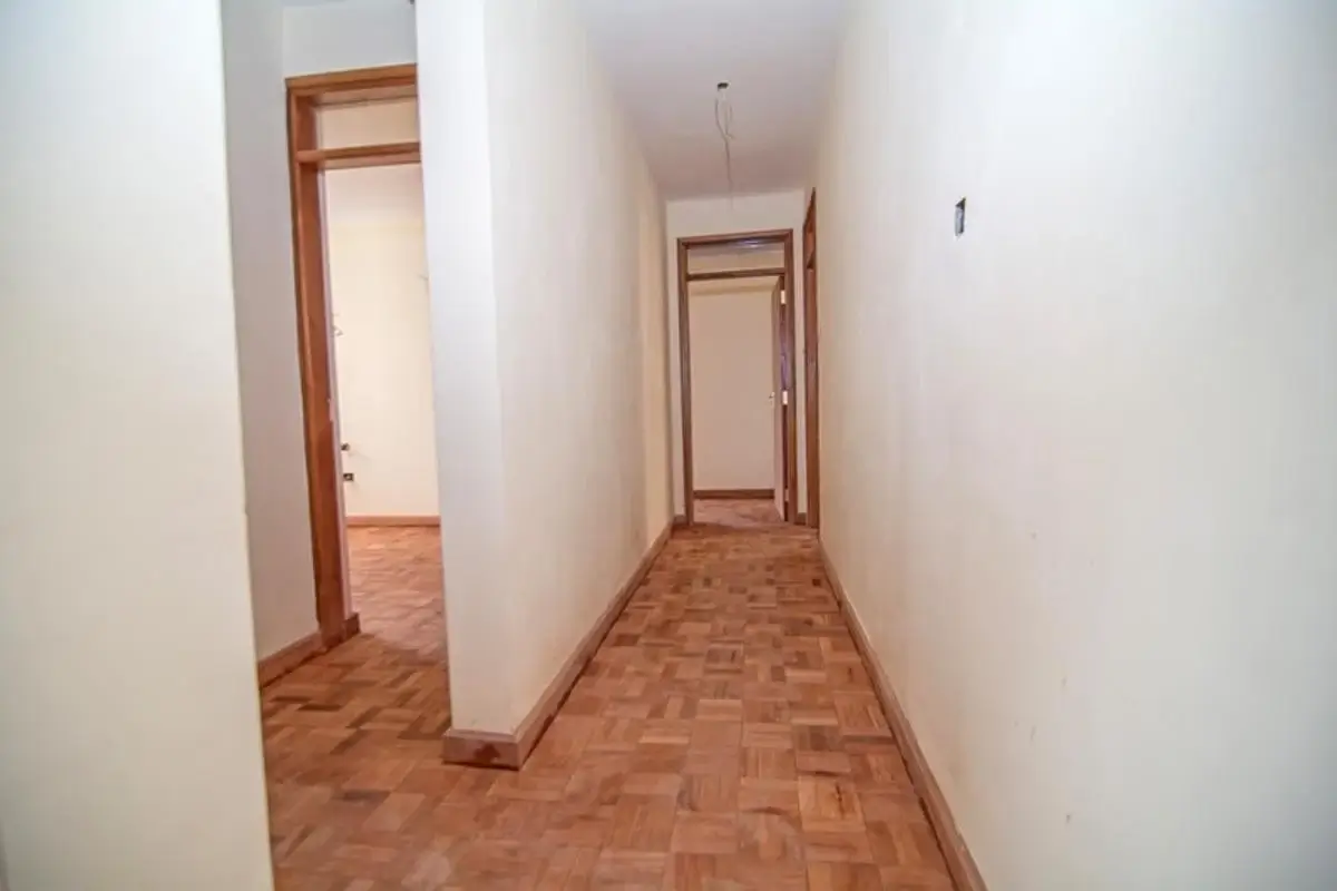 Long hallway with wooden parquet flooring and white walls