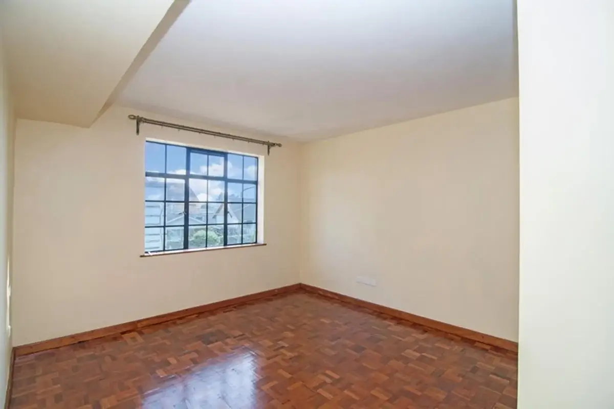 Empty bedroom with wooden floor and barred window