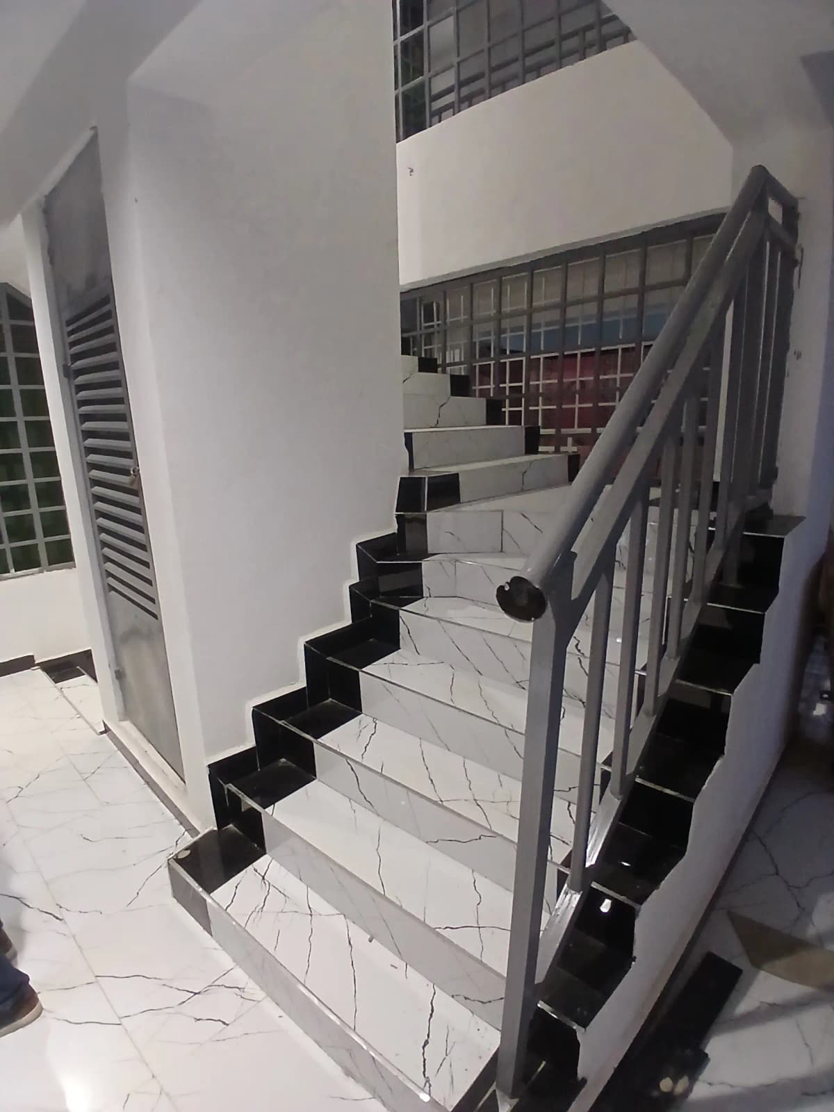 Interior staircase with black metal railings and white walls