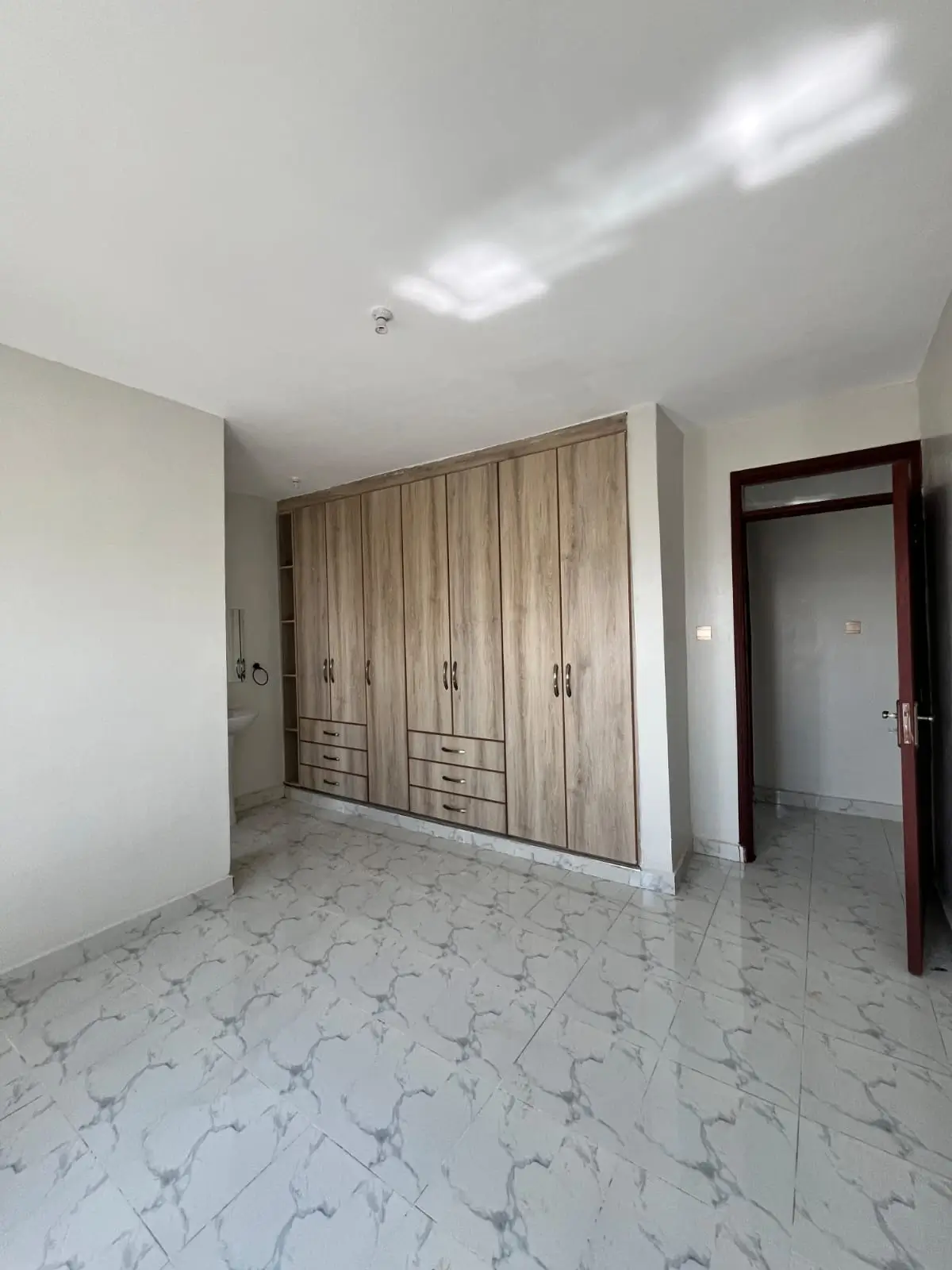 Spacious bedroom with built-in wooden wardrobes and tiled flooring