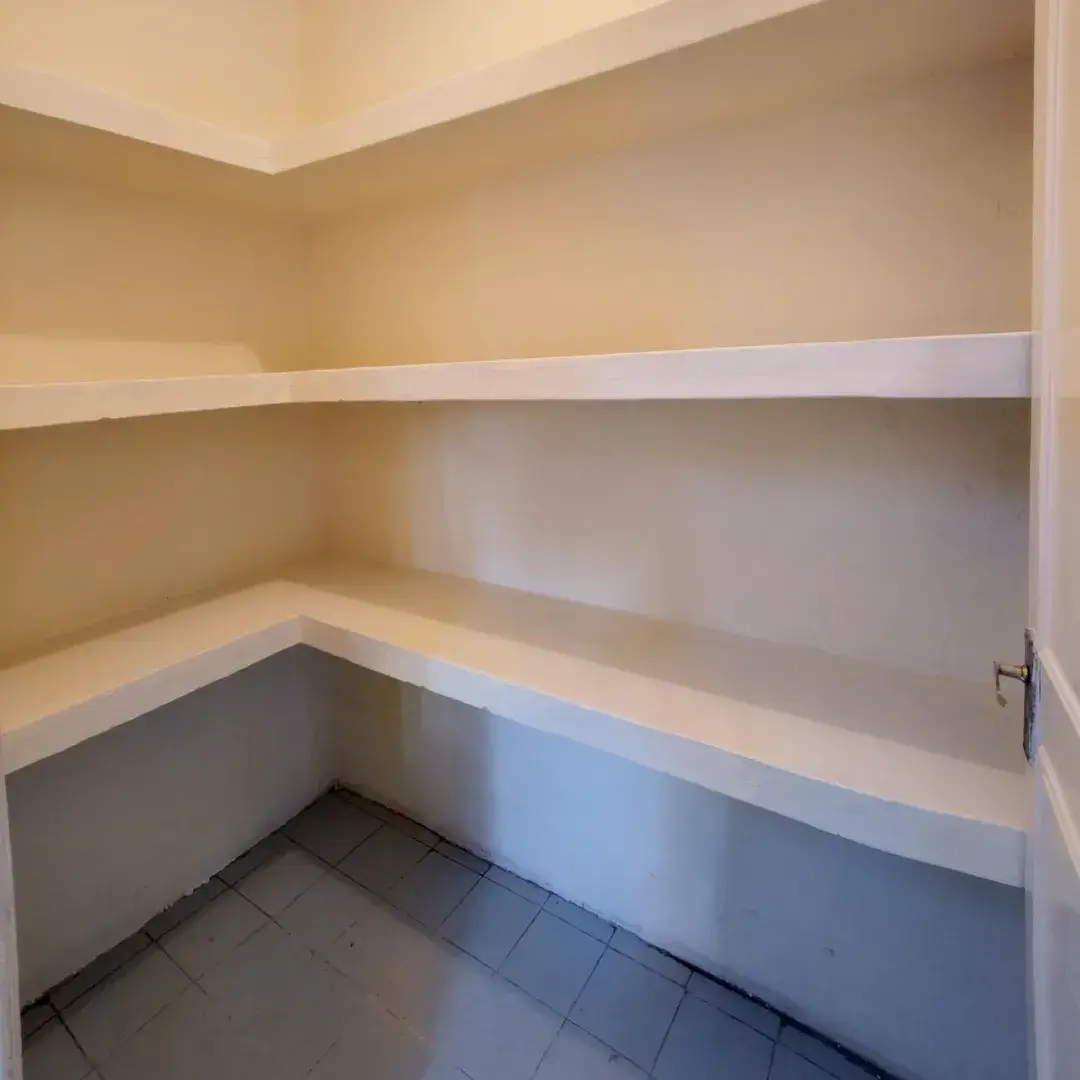 Empty pantry with white shelving and tile flooring