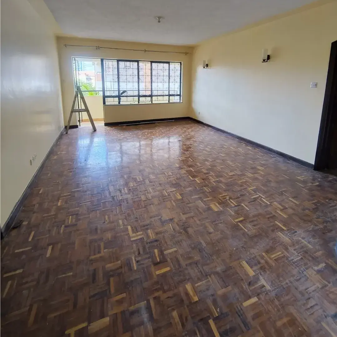 Spacious empty living room with herringbone parquet flooring.
