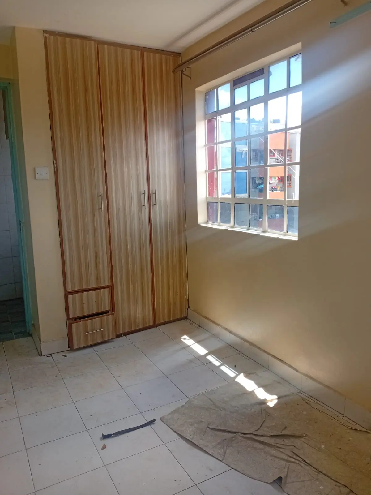 Bright bedroom with wooden wardrobes and tiled flooring