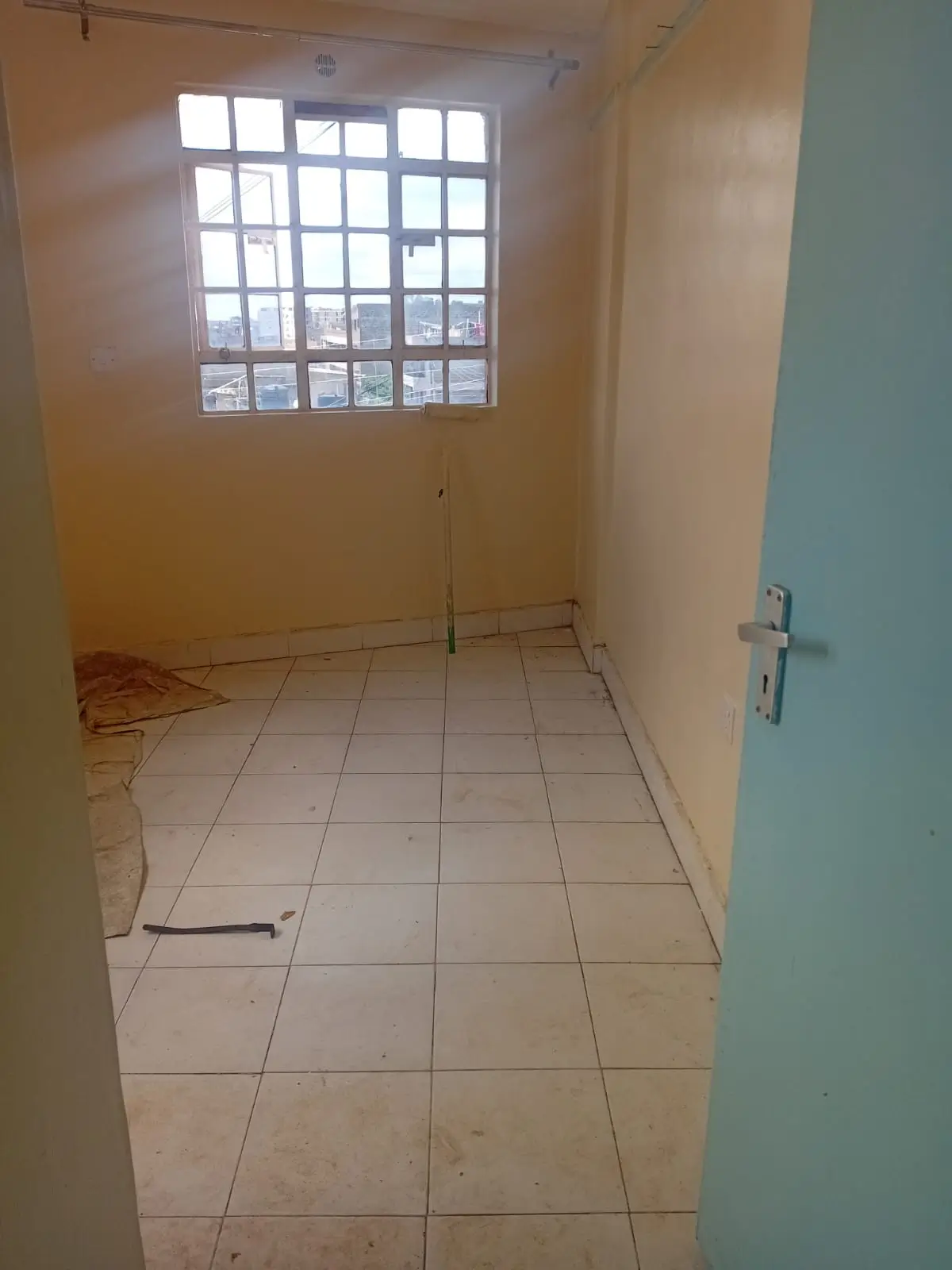 Empty bedroom with large window and tiled flooring