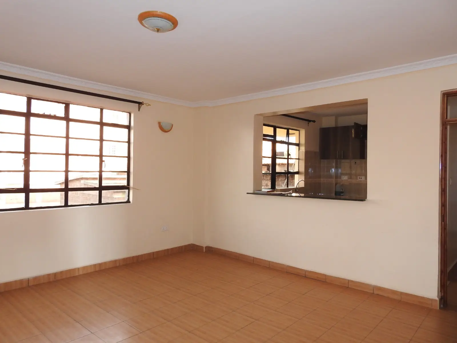Spacious living room with terracotta floor and large windows