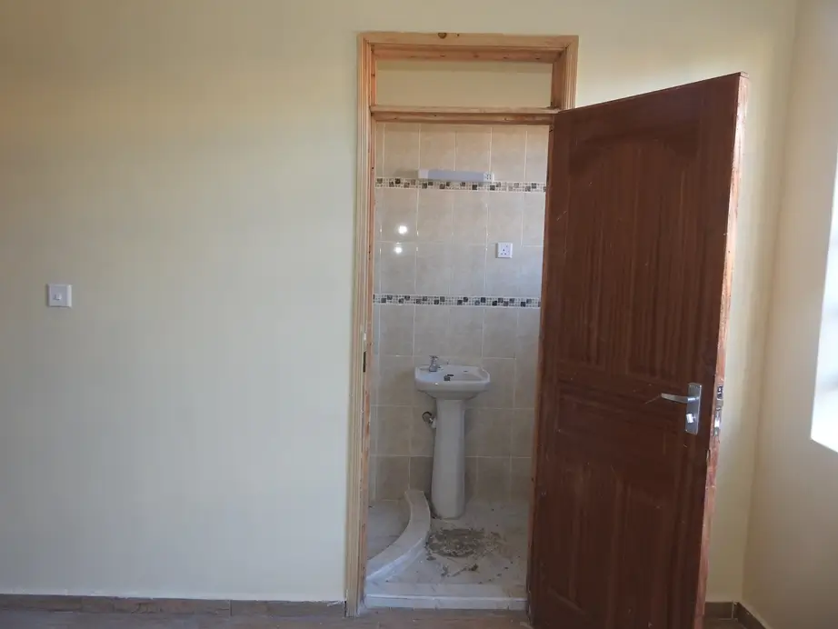 Compact bathroom with pedestal sink and tiled walls