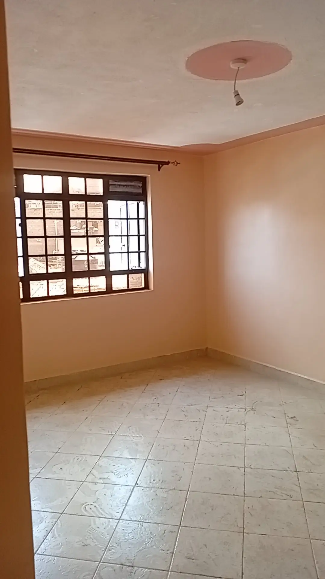 Empty bedroom with tiled floor and barred window
