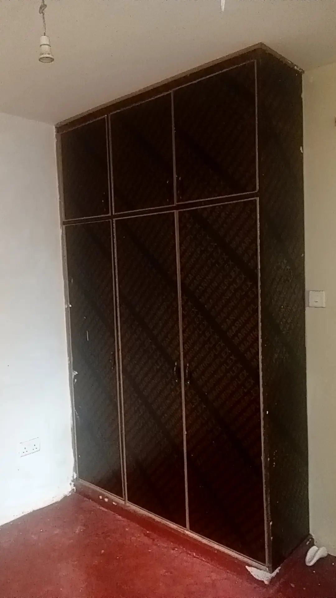 Dark wooden wardrobe closet in bedroom with red floor