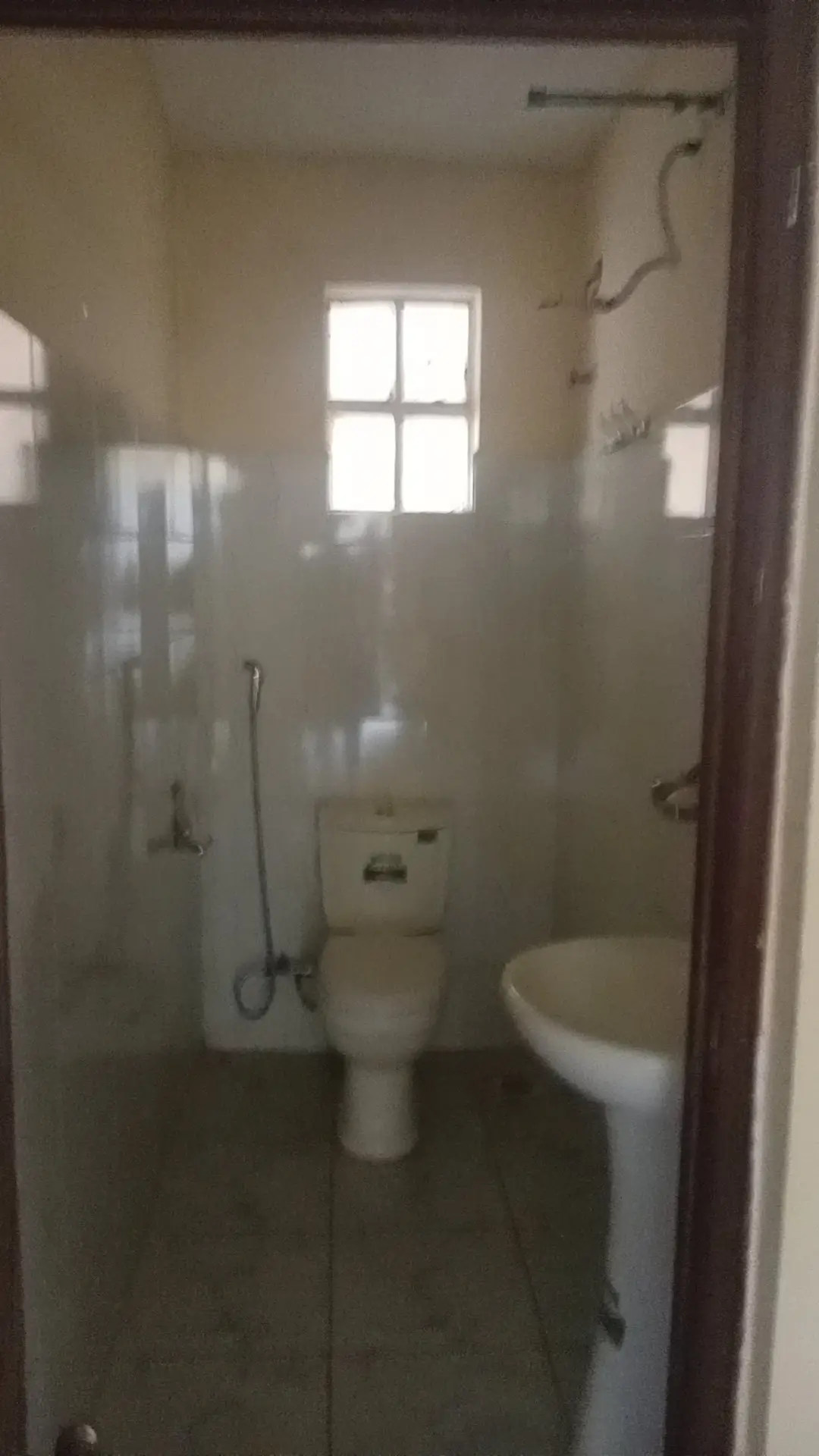 Compact bathroom with toilet, sink, shower area, natural light