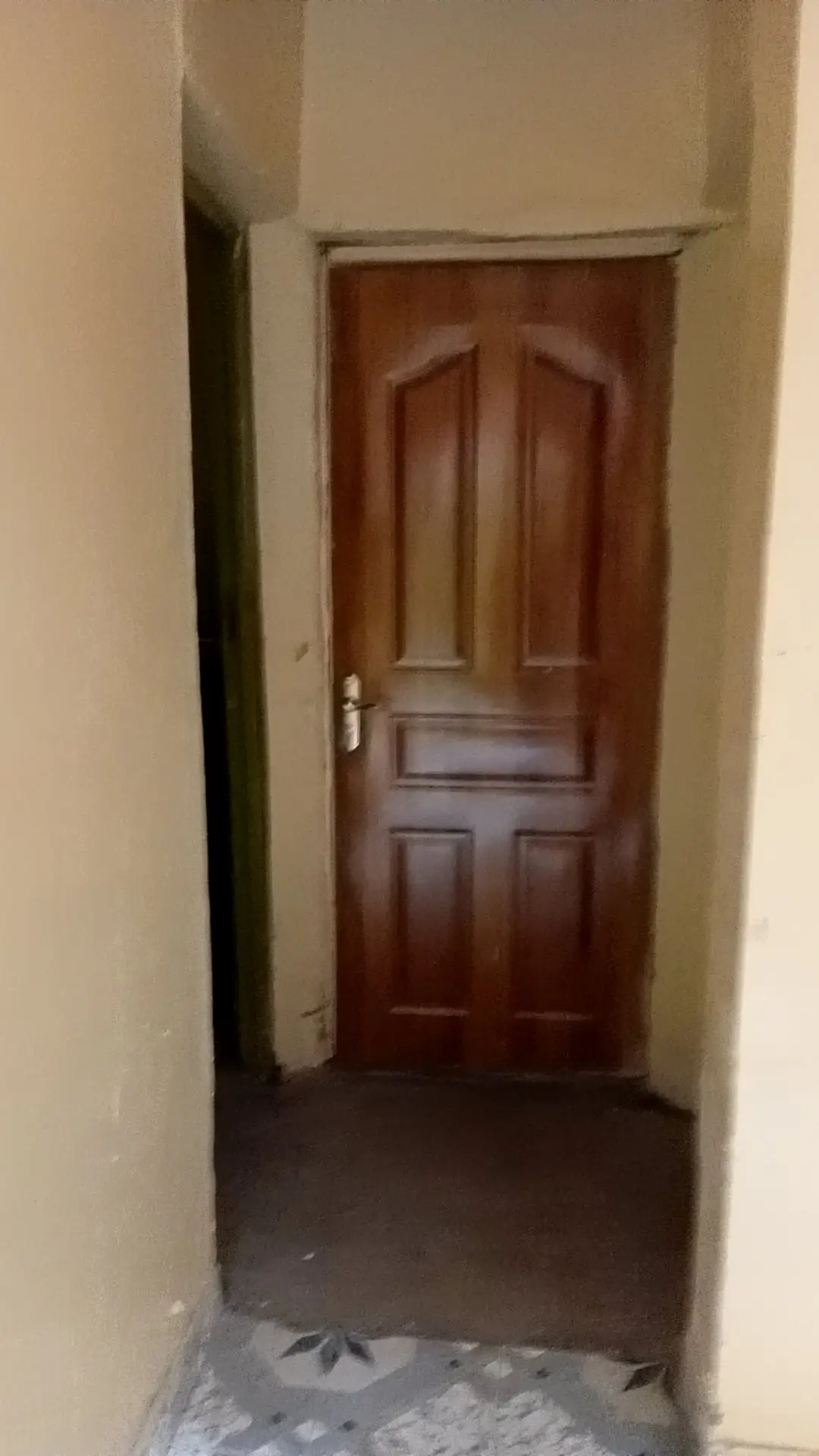 Narrow corridor with wooden door and beige walls