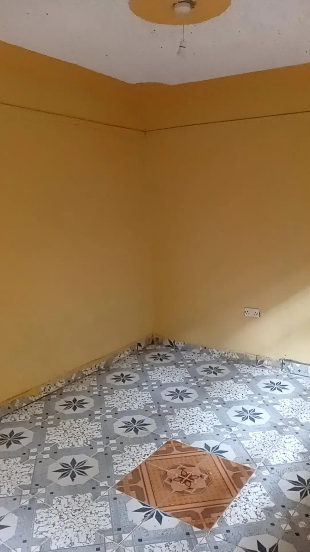 Empty bedroom with yellow walls and patterned floor tiles