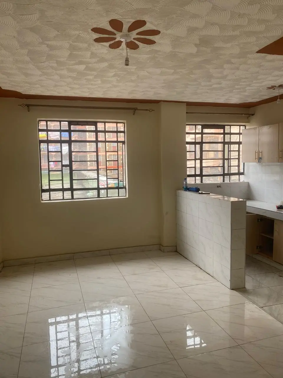 Open-plan kitchen with counter and living area, bright windows